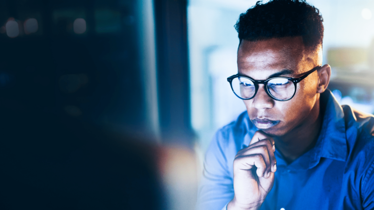 Man wearing glasses staring at computer screen